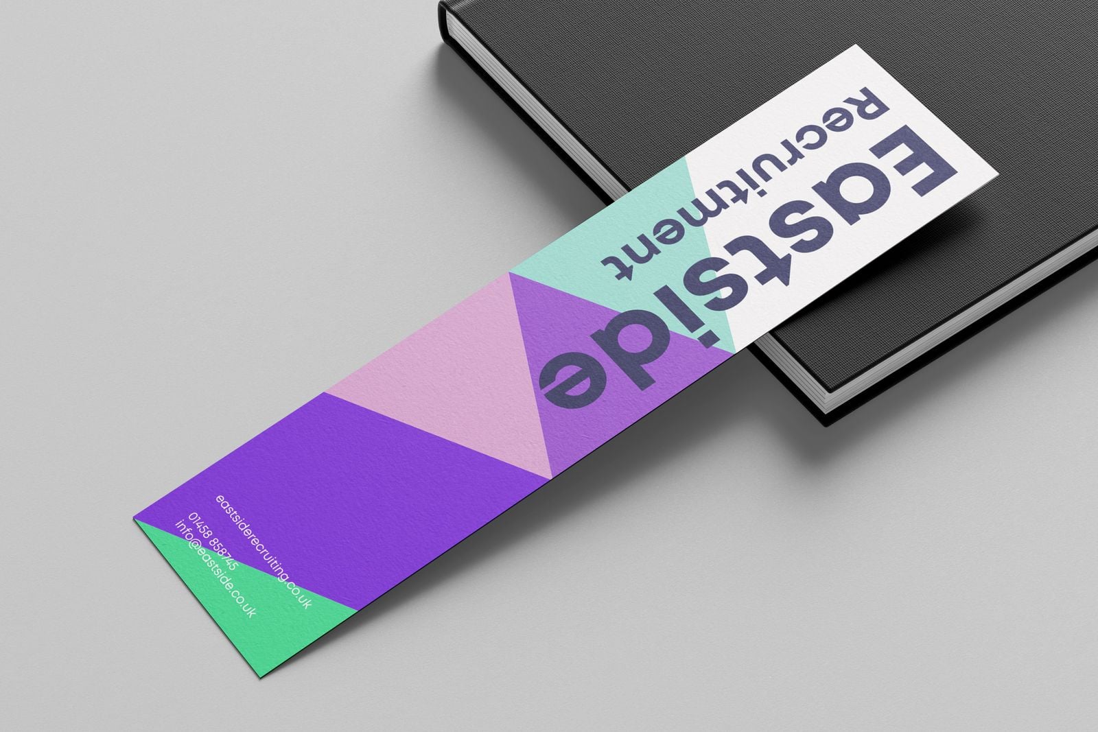 Purple and green recruitment bookmark resting on a black notebook