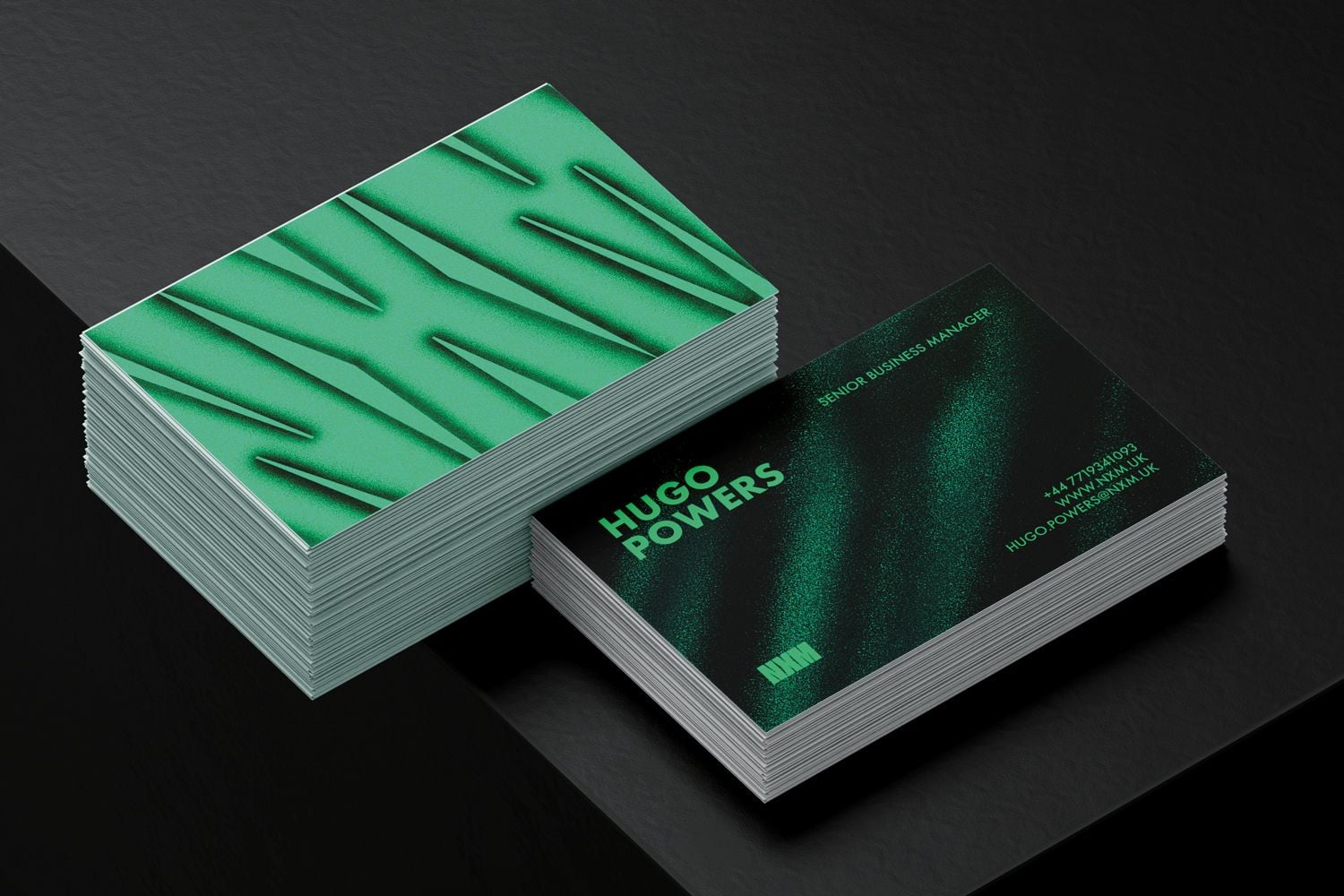 Green patterned business cards in two stacks on a black surface