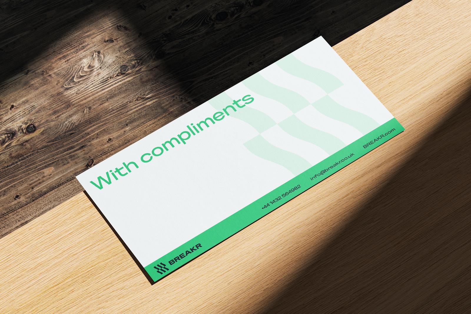 Green and white “With compliments” slip on a wooden surface