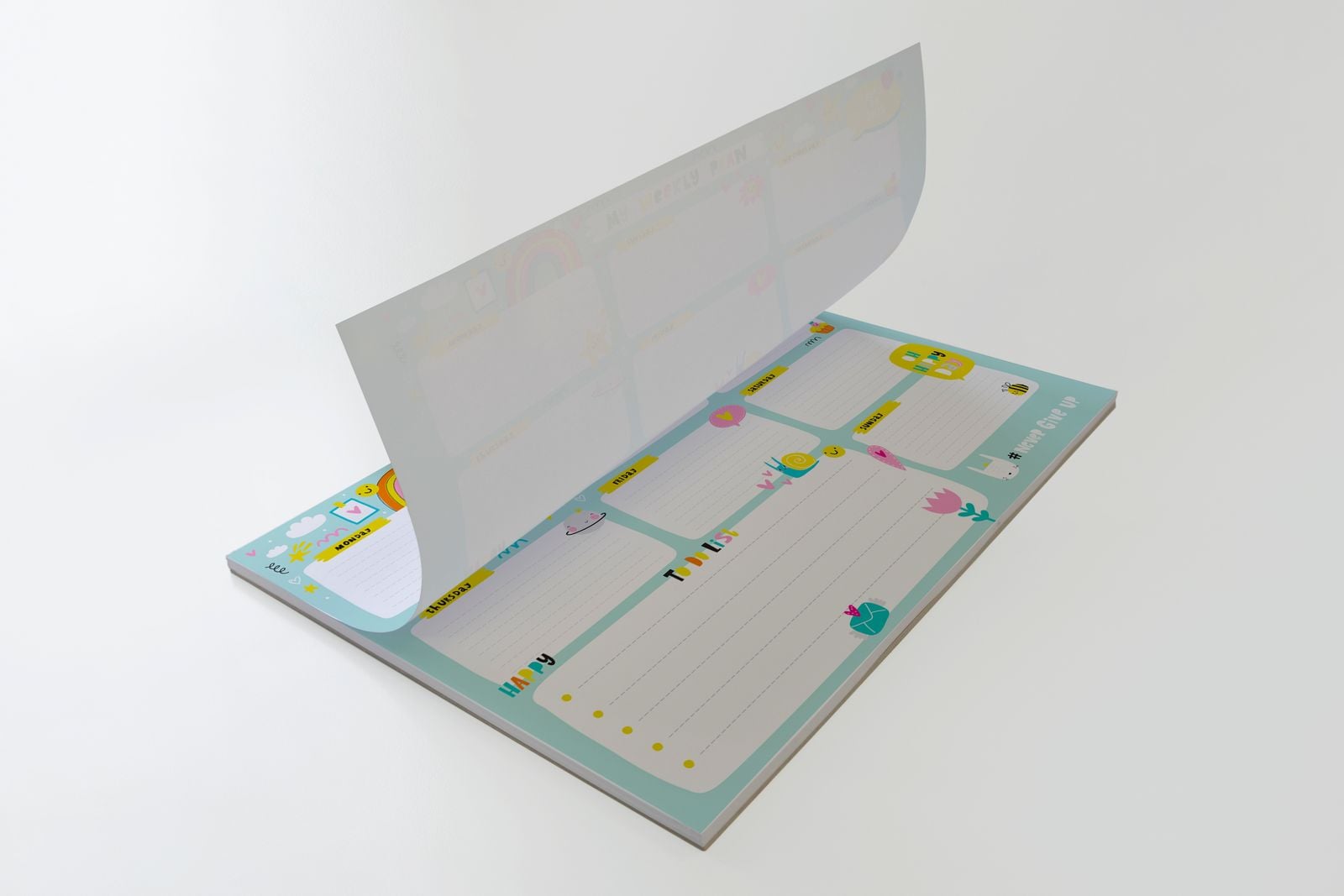 Desk pad with its top sheet lifting to show the planner layout beneath
