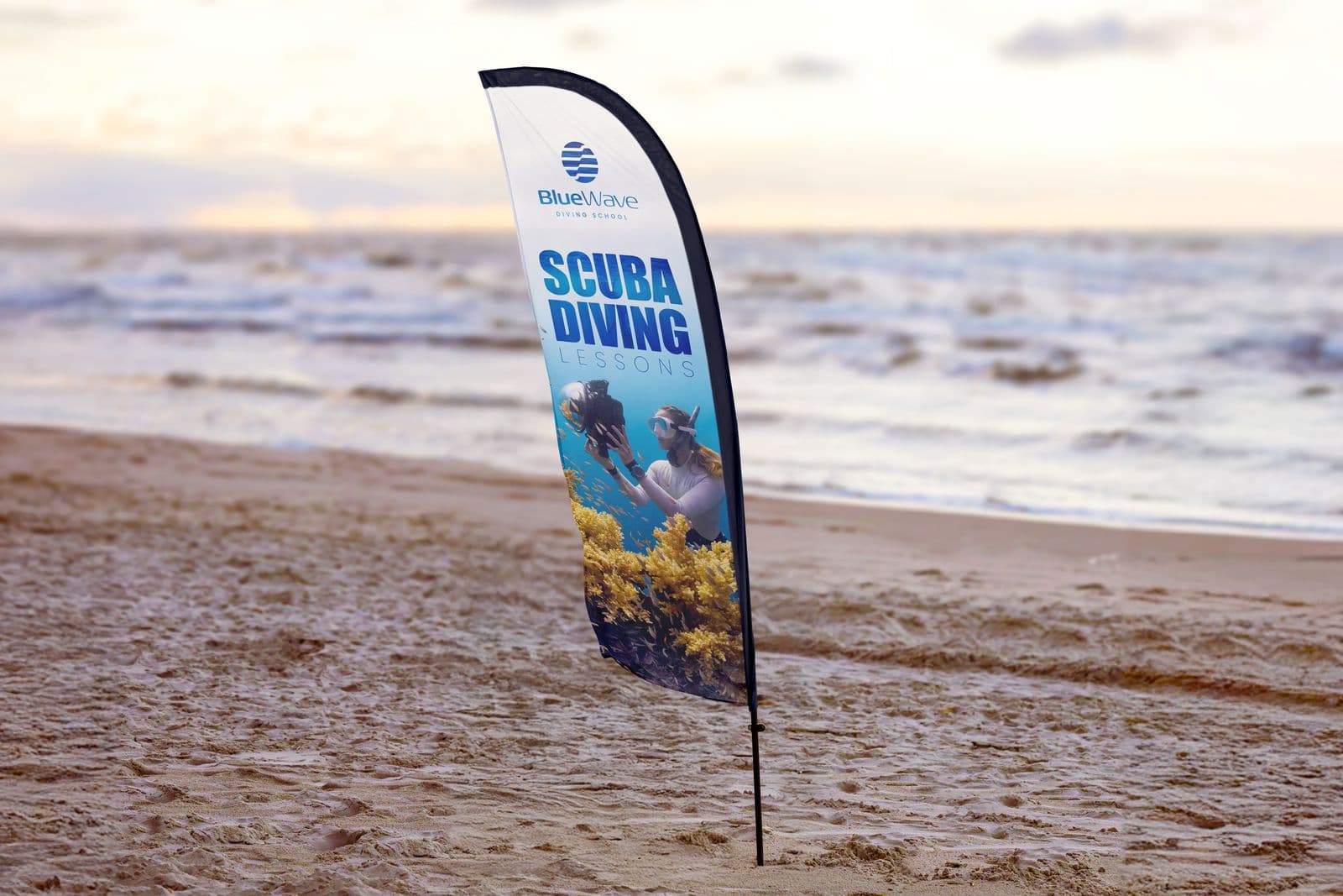 Scuba diving feather flag planted in the sand on a beach