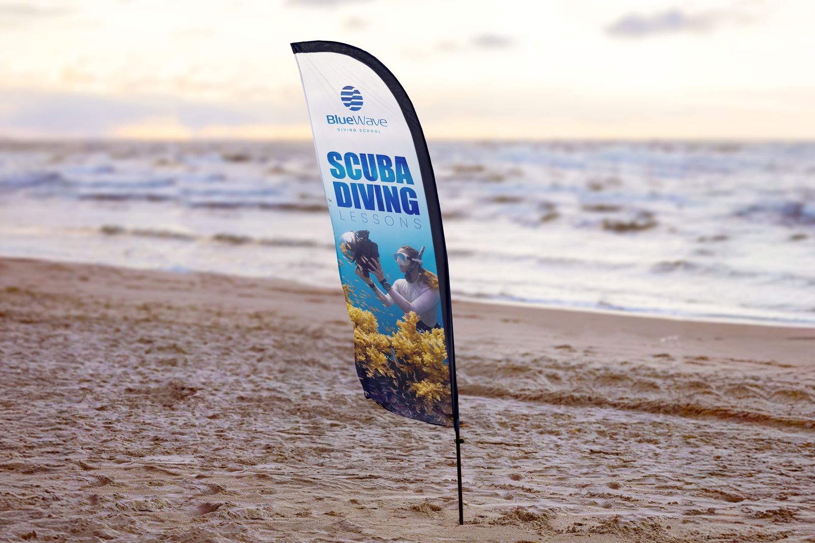 Scuba diving feather flag planted in the sand on a beach