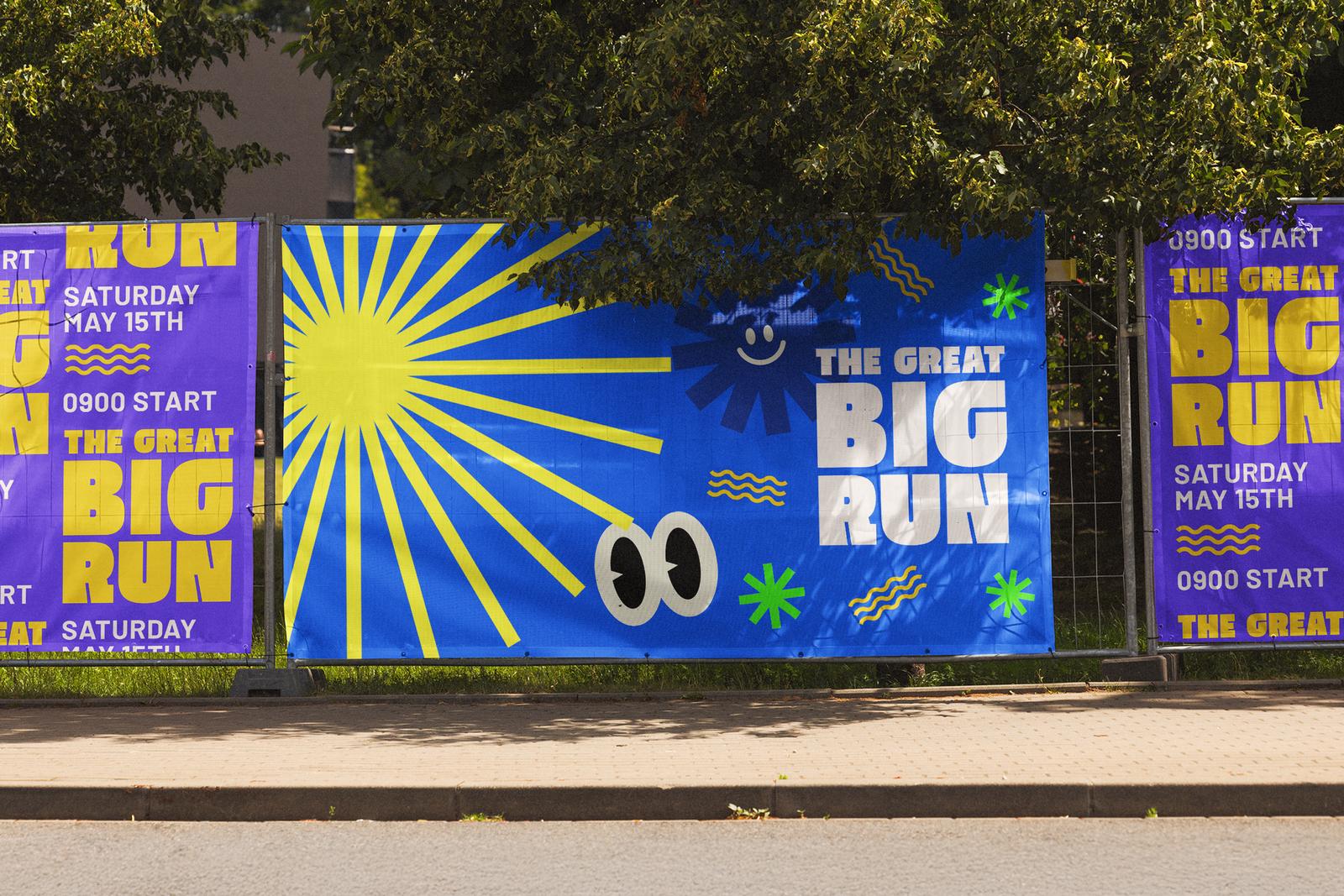 Blue and purple fun run covers on a row of Heras fence panels beside a pavement