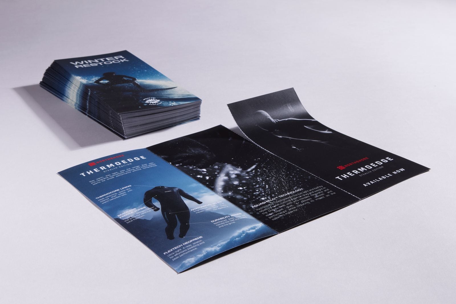 Stack of folded wetsuit leaflets beside one opened out to show its tear-off panel