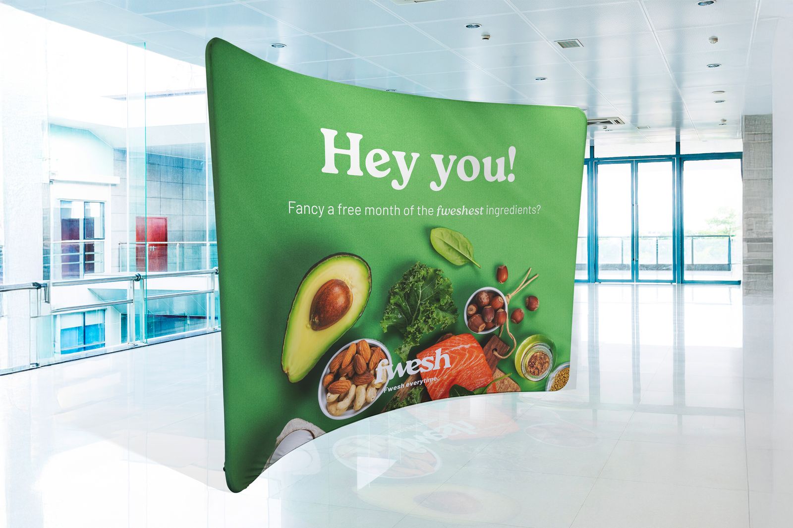 Curved green stretch fabric display with a fresh food graphic in a bright atrium