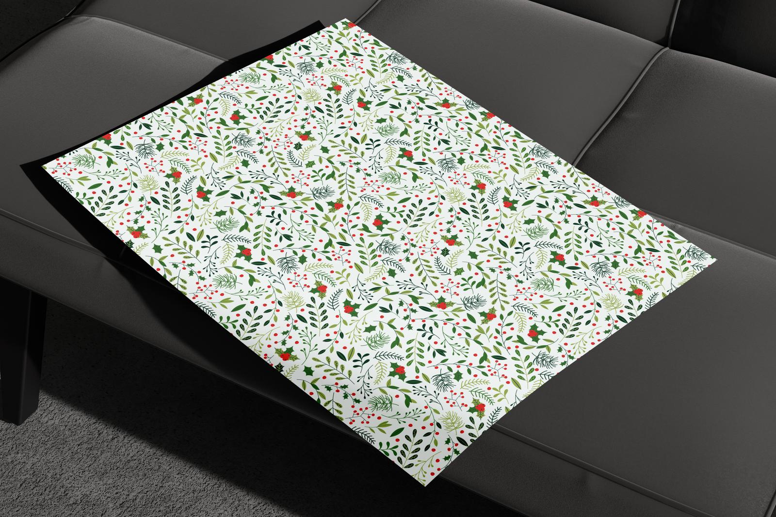 Flat sheet of holly and berry wrapping paper on a black sofa